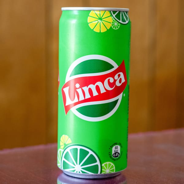 A vibrant green Limca soda can with a red and white logo, featuring lime slices.