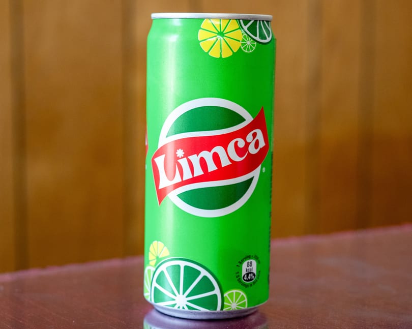 A vibrant green Limca soda can with a red and white logo, featuring lime slices.